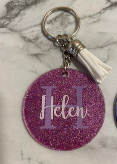 two personalized keychains with the word hello on one side and an i on the other