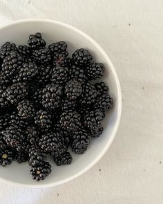 a white bowl filled with blackberries on top of a table