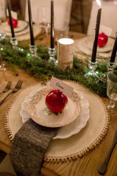 a table set for christmas with place settings, candles and napkins on the plates