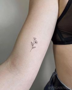 a woman's arm with a small flower tattoo on the left side of her arm