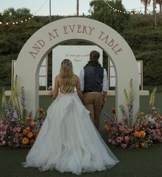 a bride and groom standing in front of a sign that says and at every table