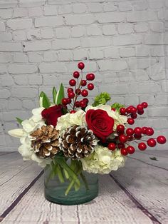 a vase filled with white and red flowers on top of a wooden table next to a brick wall