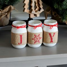 three mason jars decorated with red and white snowflakes are sitting on a table