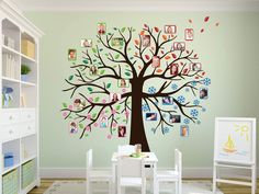 a child's room with a large tree painted on the wall and pictures hanging from it