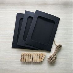 three black square frames sitting on top of a table next to twine and string