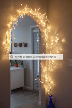 an arch decorated with lighted branches in the hallway is lit up by lights on the wall