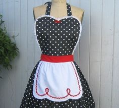 a black and white polka dot apron on a mannequin with a red ribbon