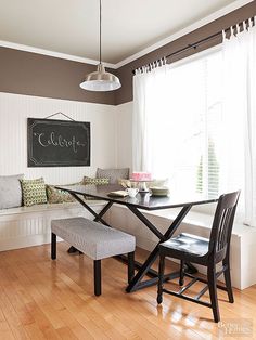 a dining room table and bench with a chalkboard on the wall