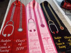 three graduation sashes with the names of each class and year on them, sitting on a table