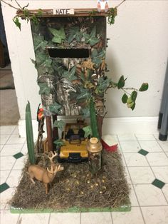 a toy truck is parked in front of a fake tree house with plants and deer