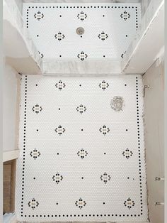 a bathroom with white tile and black dots on the wall