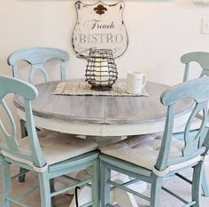 a dining room table with chairs around it and a sign on the wall above it