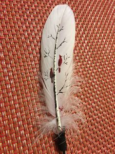 a white feather with red birds on it sitting on top of a woven table cloth