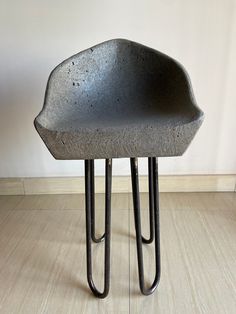 a concrete stool sitting on top of a hard wood floor next to a white wall