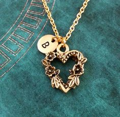 a gold necklace with a heart and flowers on the bottom is sitting on a green surface