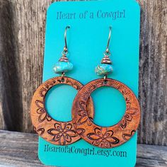 These hoop style earrings feature a hand stamped design, are dyed medium tan and topped with genuine Campitos mine turquoise beads...earrings hang from hand formed copper French style ear wires... Do you have sensitive ears?  I offer titanium ear wires and am happy to replace them on these earrings.  Simply add the listing below to your order:  https://www.etsy.com/listing/1461783353/titanium-ear-wires-hypoallergenic-ear?click_key=d2deb59f130b3505244212b93ed2f86aac9751ee%3A1461783353&click_sum=5 Bohemian Stamped Earrings, Turquoise Bead Earrings, Jewelry Western, Turquoise Hoop Earrings, Turquoise Hoops, Leather Earring, Boho Cowgirl, Cowgirl Jewelry, Western Earrings