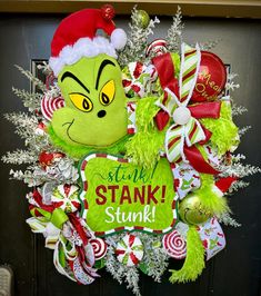 Introducing our Christmas Grinch Head Wreath, a whimsical and festive addition to your holiday decorations. This eye-catching wreath is expertly crafted and designed to bring a touch of Christmas cheer to your personal home. Adorned with vibrant red, green, white, and yellow decorations, including ribbons and ornaments, this wreath captures the mischievous spirit of the beloved Grinch. Hang it proudly on your door and watch as it becomes a conversation starter for all who pass by. Made with utmost attention to detail, this Grinch Head Wreath promises to be a standout piece that will spread holiday joy and add a dash of playfulness to your home this Christmas season. Grinch Front Door Decor, Christmas Grinch Wreath, Grinch Head, Yellow Decorations, Front Door Christmas Decorations, Wood Wreath, Whimsical Wreaths