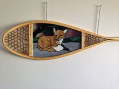 a wooden wall hanging with a painting of a fox sitting on it's side