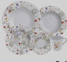 a set of four plates and two cups with flowers painted on the front, along with a matching cup and saucer