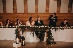 a group of people sitting at a table with flowers and candles in front of them