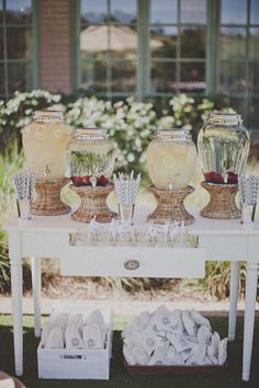 a table topped with vases filled with flowers next to a white table covered in food