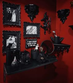 there is a shelf with pictures on it and other decorations in front of the red wall