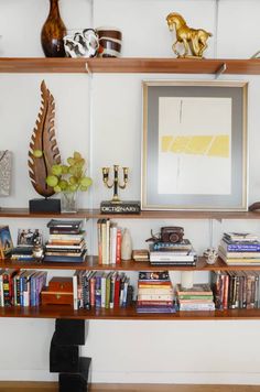 a bookshelf filled with lots of books next to a painting and vases