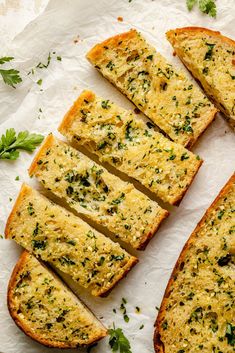 slices of garlic bread with parsley on the side next to some garlic and herbs