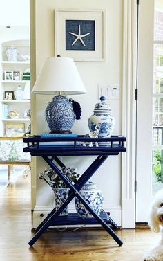 a dog sitting on the floor in front of a table with vases and a lamp