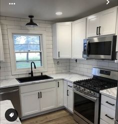 a kitchen with white cabinets and stainless steel stove top oven in the middle of it