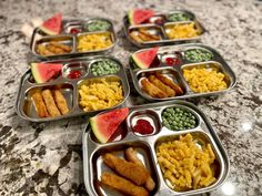 several trays filled with different types of food on top of a marble countertop