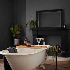 a bathtub in a bathroom with blue walls and wood flooring next to a mirror