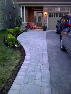 a car parked in front of a house next to a driveway with landscaping around it