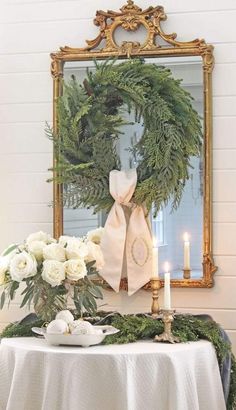 a table topped with a wreath and candles next to a white table cloth covered table