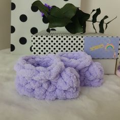 a pile of purple towels sitting on top of a white bed next to a box