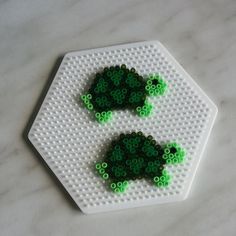 two green beads are placed on top of a white hexagonal object that looks like an animal