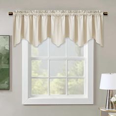 a window with a white valance hanging on the side of it next to a lamp