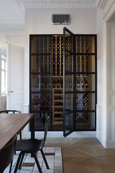 a dining room table with chairs and a wine rack in the wall between two doors