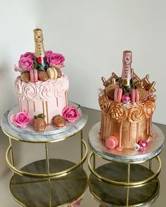 two cakes decorated with pink roses and champagne bottles are on gold trays next to each other