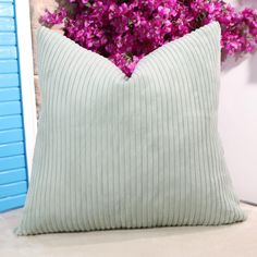 a pillow sitting on top of a table next to purple flowers