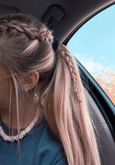 a woman sitting in the back seat of a car with her hair in a pony tail braid