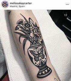 a black and white vase with flowers in it is on the left arm, next to another tattoo