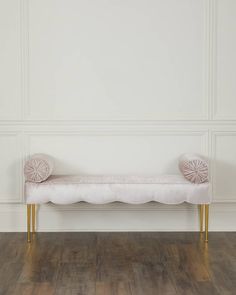 a white bench sitting on top of a hard wood floor covered in pink velvet cushions