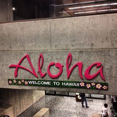 the welcome sign to aloha is painted in bright pink and green letters that read, welcome to hawaii