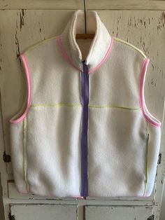 a white and pink vest hanging on a door