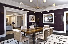 an elegant dining room with purple walls and white trimmings, along with beige upholstered chairs