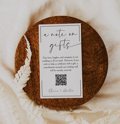 a wooden plate with a note on it sitting on a white cloth covered tablecloth