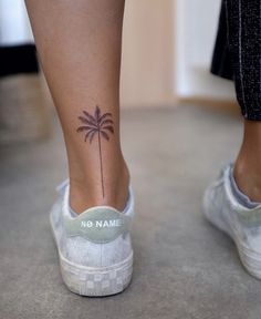 a woman's foot with a small palm tree tattoo on it