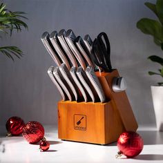 a wooden knife holder with knives and other kitchen utensils in front of it