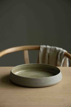 a wooden table with a white plate on it and a chair in the back ground